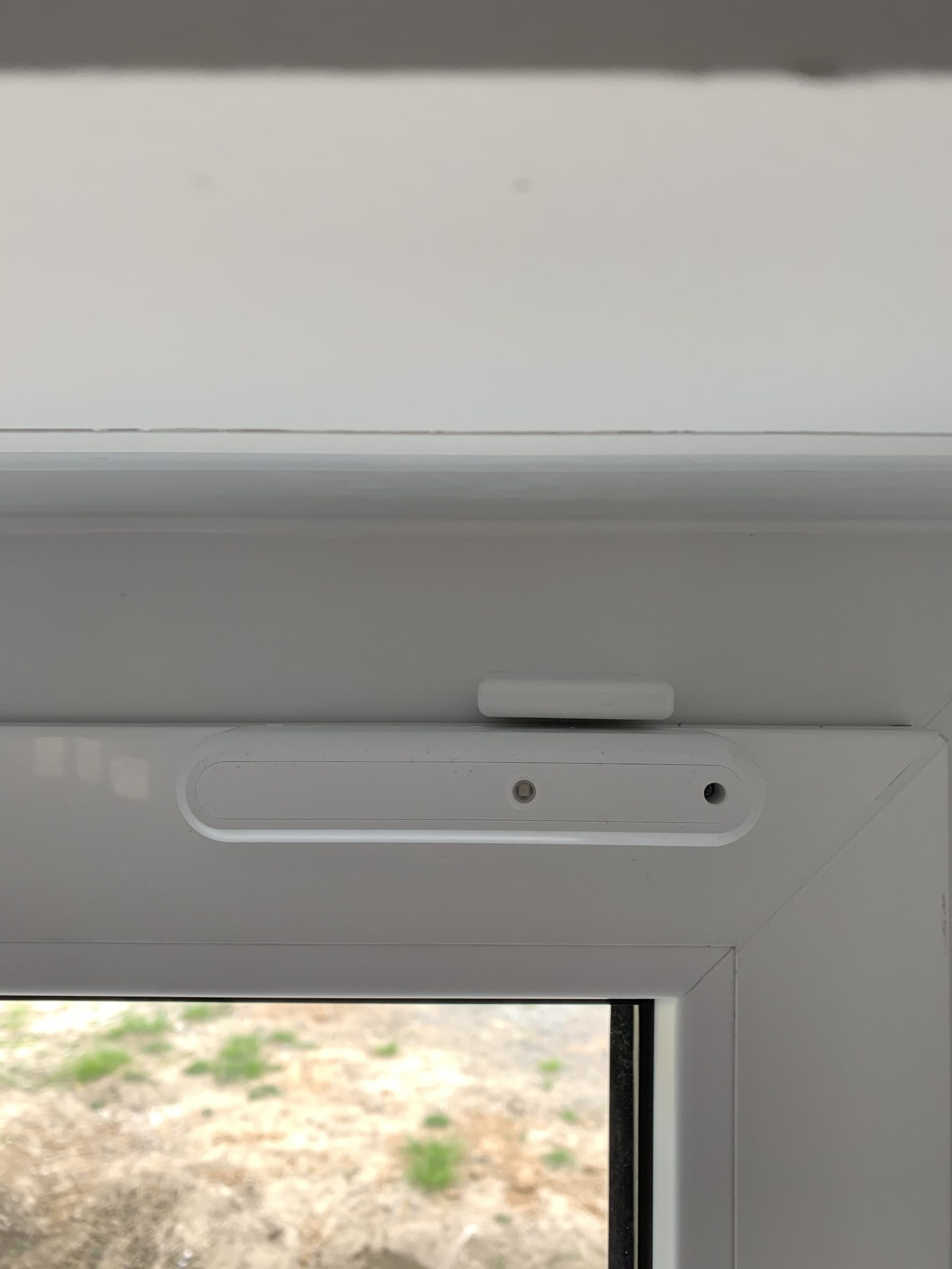 Ein installierter Glasbruchmelder auf einem Fensterrahmen.